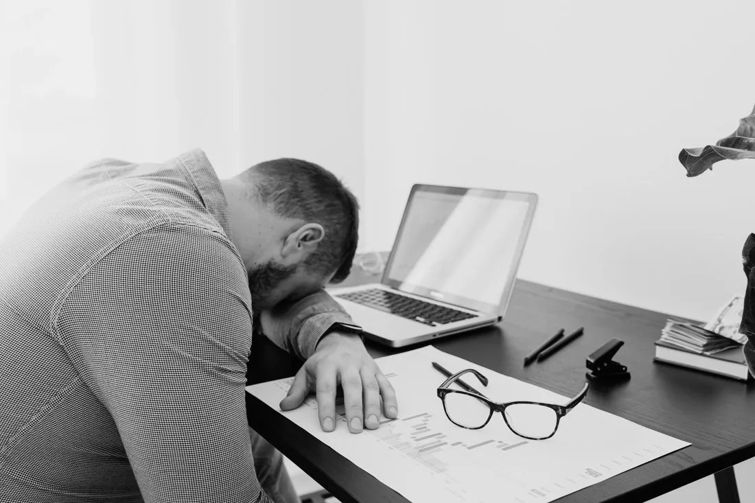 Patron épuisé, la tête sur son bureau à côté de son ordinateur