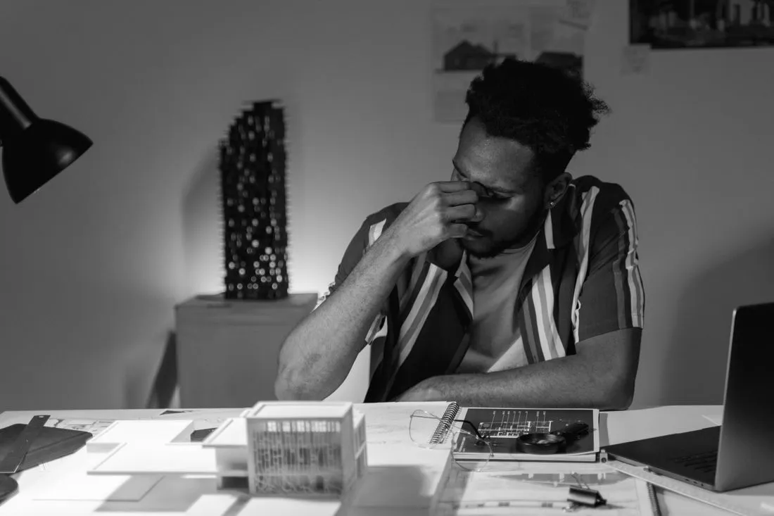 Patron fatigué à son bureau, la main sur le visage, entouré de dossiers