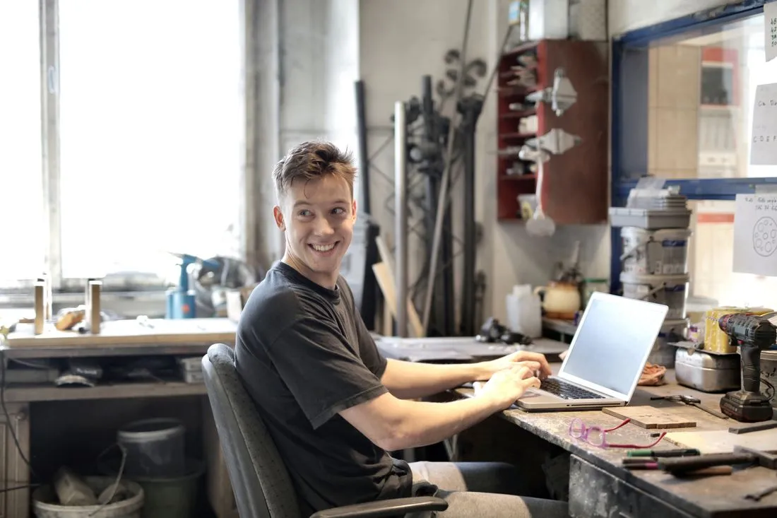 Artisan souriant devant son ordinateur dans son atelier