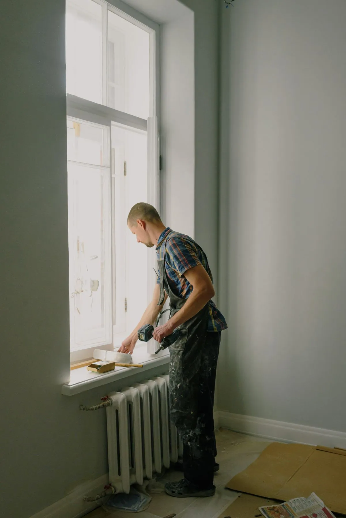 Artisan qui pose une fenêtre dans un appartement en rénovation