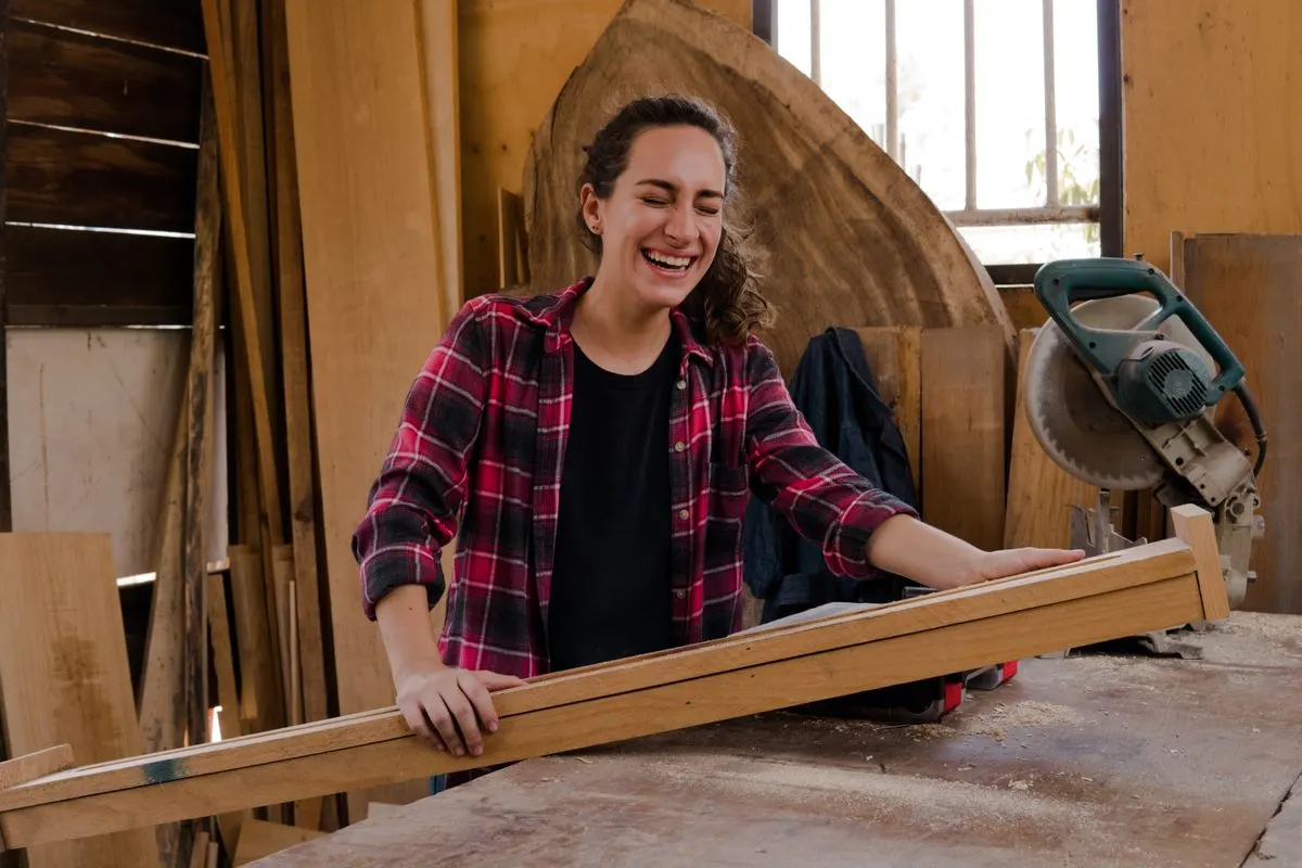 Menuisière souriante qui travaille une planche dans son atelier
