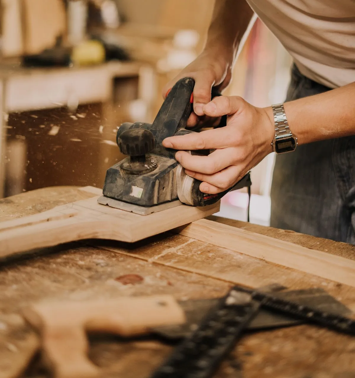 Artisan qui rabote une pièce de bois dans son atelier