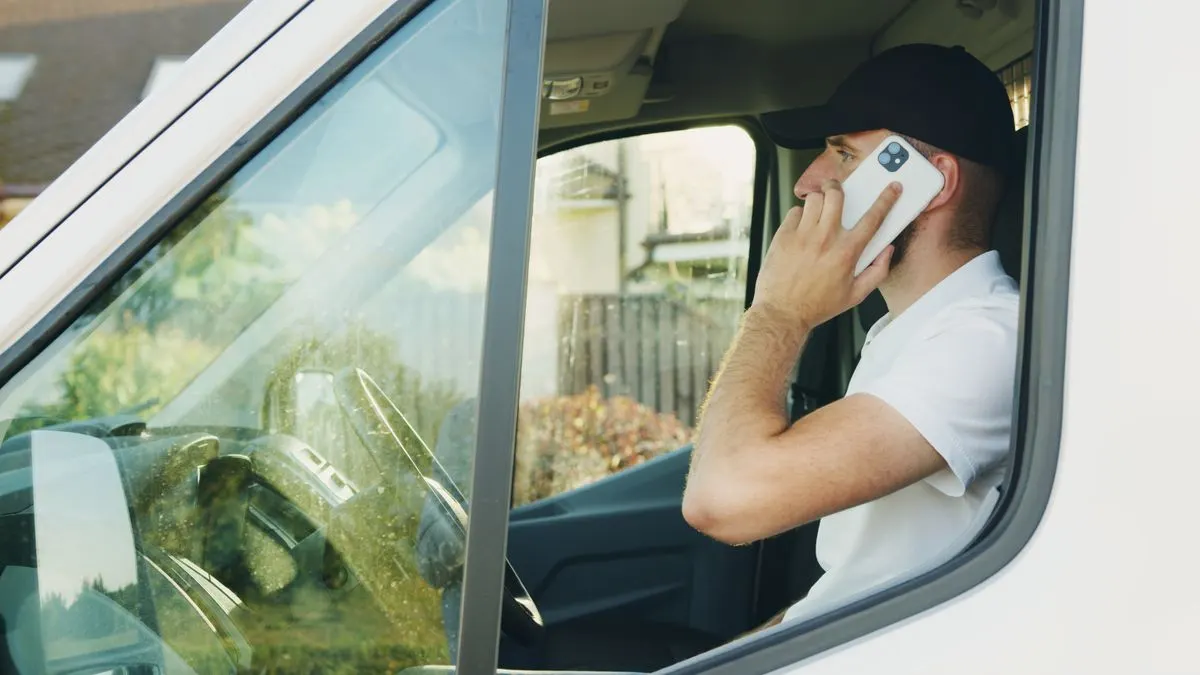 Artisan au volant de son utilitaire qui appelle un client
