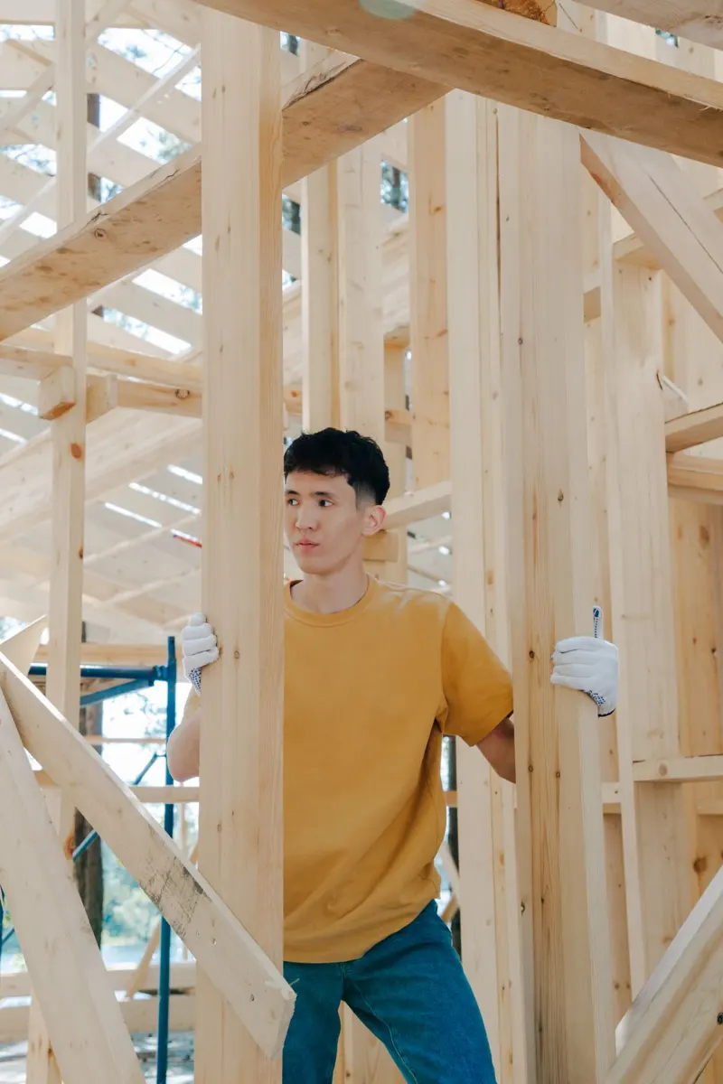 Jeune charpentier dans l’ossature bois d’une maison