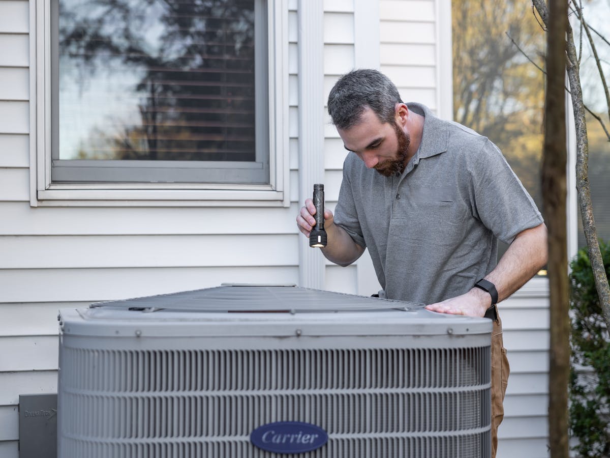 Installateur inspectant une pompe à chaleur lors d’un chantier de rénovation énergétique — logiciel BatUp pour artisans en énergies renouvelables